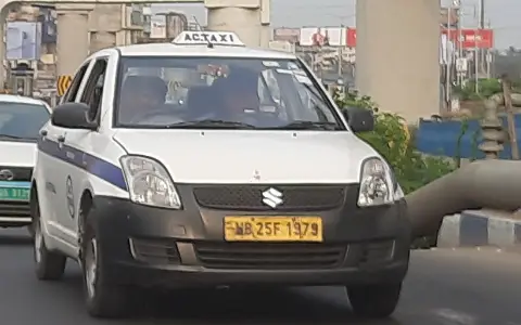 White taxi sedan with a roof sign on a city road